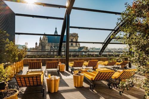 a rooftop patio with chairs and tables and a view of the city at Hôtel Madame Rêve in Paris