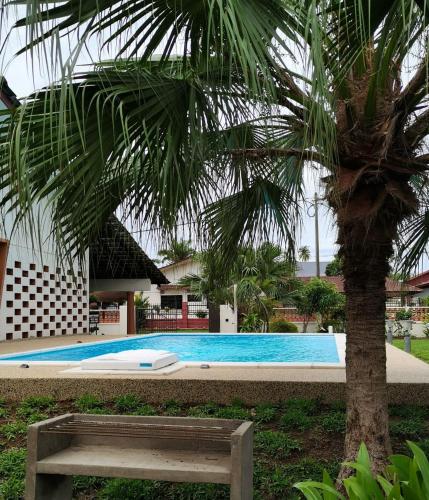 een zwembad met een bank naast een palmboom bij TS GUEST HOUSE in Kuantan