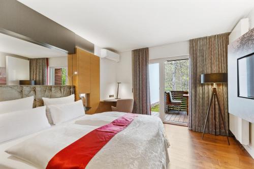 a bedroom with a large bed and a sliding glass door at Romantik Hotel Landschloss Fasanerie in Zweibrücken