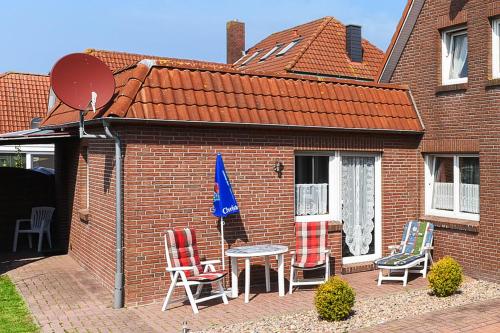 a brick house with a table and chairs on a patio at Ferienwohnung Seepferdchen in Bensersiel