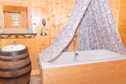 a bathtub with a shower curtain in a wooden room at La Fée Maison in Châtel-sur-Moselle