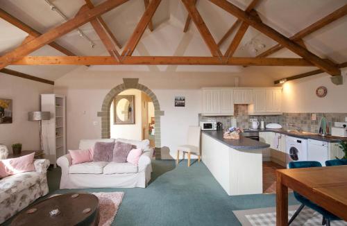 a living room with a couch and a kitchen at Spacious Swallow Cottage in Tisbury