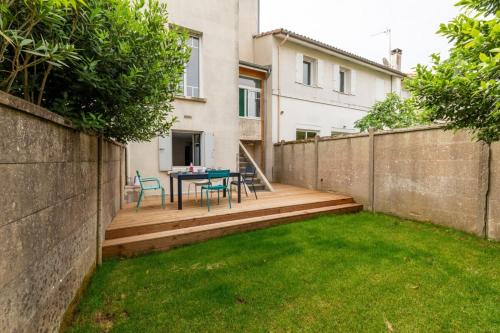 einen Hinterhof mit einem Tisch und Stühlen auf einer Holzterrasse in der Unterkunft Furnished Townhouse Ideally Located With 4 Bedrooms Large Terrace & Garden in Le Bouscat