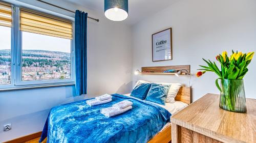 Un dormitorio con una cama azul con toallas. en Apartament Cichy - 5D Apartamenty, en Świeradów-Zdrój
