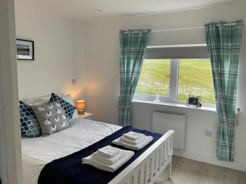 a bedroom with a bed and a window with towels at TomaX Garden Cabin Free Parking in Inverness