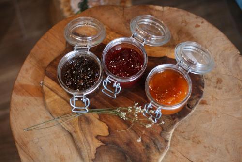four glass jars of jam on a wooden cutting board at Hostal Rural Can Pau in Cantallops