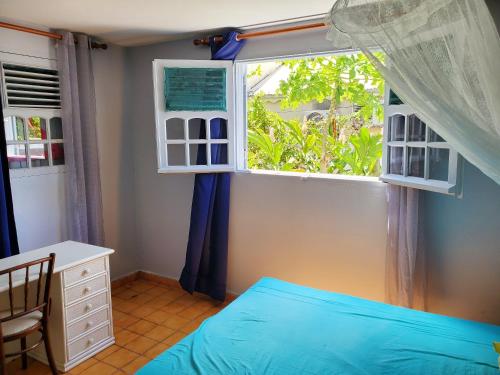 una camera con un letto blu e una finestra di Appartement d'une chambre avec jardin clos et wifi a Sainte Rose a 2 km de la plage a Sainte-Rose