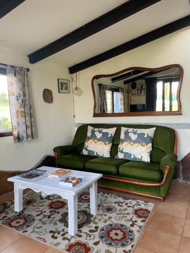 a living room with a green couch and a table at Son de Mar Hotel rural & Apartamento in Quintueles