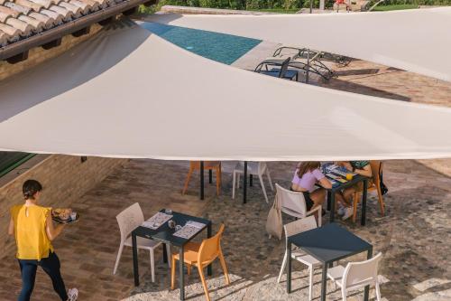 a man walking under a white tent with people sitting at tables at Relais Cocci Grifoni - Panoramic Wine Resort in Offida