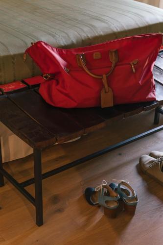 a red bag and pair of shoes sitting on a bed at Relais Cocci Grifoni - Panoramic Wine Resort in Offida