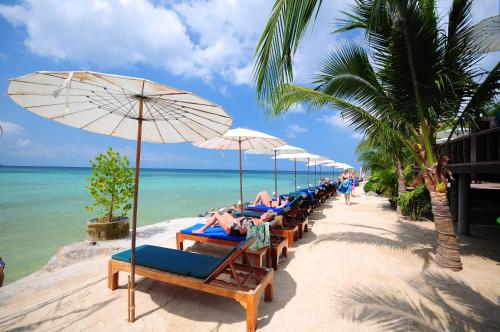 a row of beach chairs with umbrellas on a beach at Haad Yao Bayview Resort & Spa - SHA plus Certified in Haad Yao