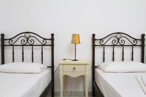 a bedroom with two beds and a night stand with a lamp at Saint Thomas Village in Lefkada