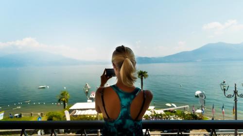 a woman taking a picture of the water at Residence Casa e Vela in Oggebbio