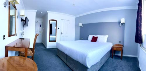 1 dormitorio con 1 cama blanca grande y escritorio en Roman Way Hotel en Cannock