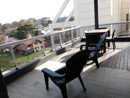 ein Balkon mit zwei Stühlen und einem Tisch auf einem Gebäude in der Unterkunft Libertador Norte Departamentos in Pinamar