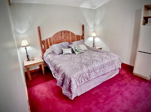 um quarto com uma cama grande e alcatifa rosa em Cedar Creek Cabins em Eureka Springs