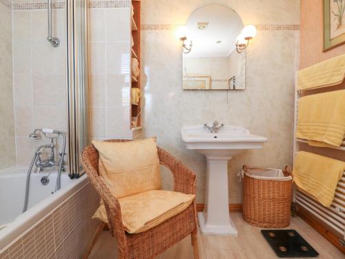 a bathroom with a wicker chair and a sink at Old Hollow Cottage in Southport