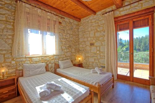 duas camas num quarto com uma parede de pedra em Villa Vrisses by PosarelliVillas em Vryses