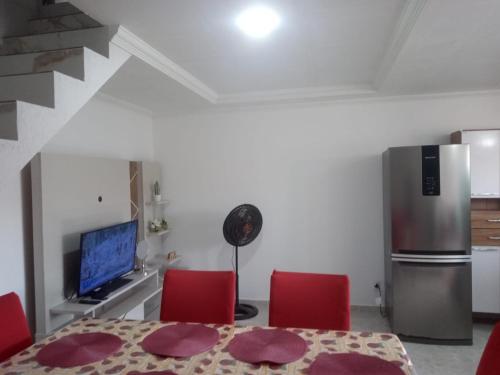 una cucina con tavolo, sedie rosse e frigorifero di Apartamento Duplex Mobiliado em São Pedro da Aldeia a São Pedro da Aldeia
