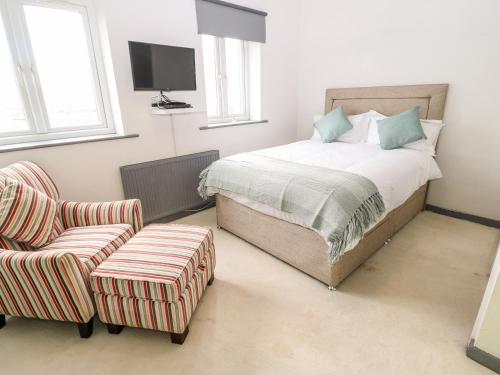 1 dormitorio con 1 cama, 1 silla y TV en Midway House en Keighley