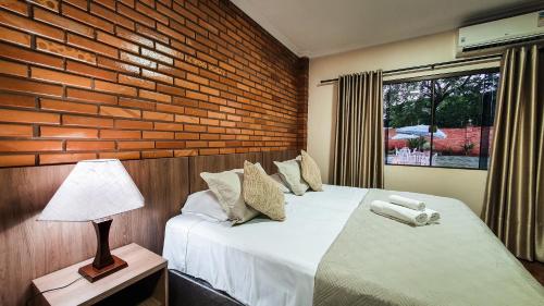 a bedroom with two beds and a brick wall at Pousada Rio Das Aguas in Foz do Iguaçu