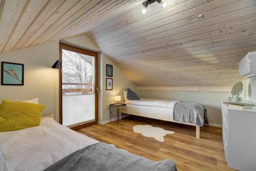 sypialnia z 2 łóżkami i drewnianym sufitem w obiekcie Przy Cegielni w mieście Tylicz