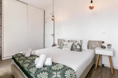 a white bedroom with a large bed with pillows at Casa Trilhos da Serra in Alcobertas