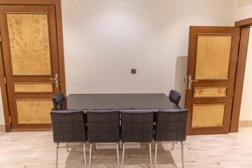 a table and chairs in a room with two doors at Mostar Resort in Riyadh