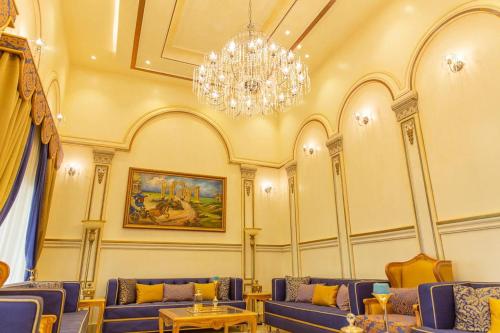 a living room with blue couches and a chandelier at Mostar Resort in Riyadh