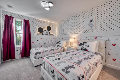 two beds in a bedroom with red curtains at Formosa Valley by UNE Homes in Orlando