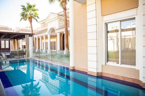 a swimming pool in front of a house with palm trees at Mostar Resort in Riyadh