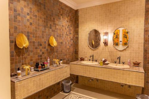 a tiled bathroom with two sinks and two mirrors at Mostar Resort in Riyadh