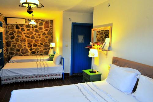a bedroom with two beds and a stone wall at Alterna Köy Evi in Sokakagzi