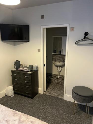 a room with a bedroom with a sink and a desk at roosevelt lodge in Skegness