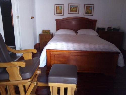 a bedroom with a wooden bed and a chair at Casa Patrimonial Abejorral - CASA GASAMA in Abejorral