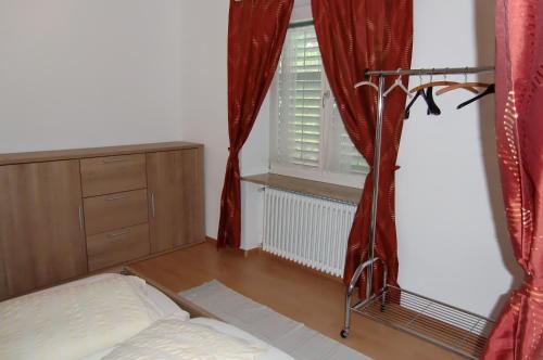 a bedroom with a bed and a window with red curtains at Neuprantl Apartments in Lana