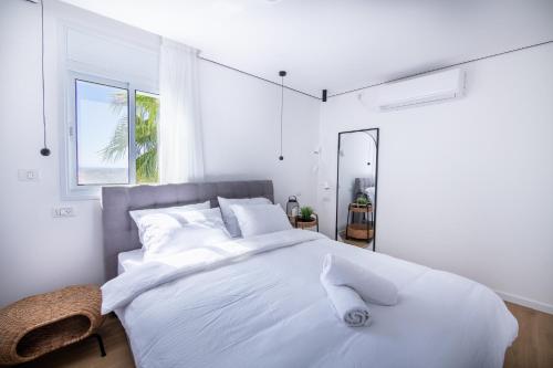 ein weißes Schlafzimmer mit einem großen Bett mit weißer Bettwäsche und Kissen in der Unterkunft Sunlight-Luxury and sea view apartment in Eilat