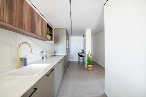 eine Küche mit weißen Arbeitsflächen, einem Waschbecken und einem Tisch in der Unterkunft Sunlight-Luxury and sea view apartment in Eilat