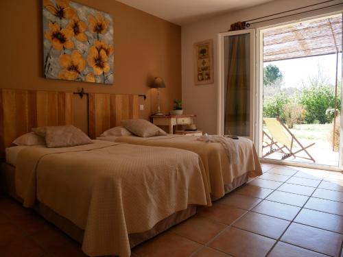 two beds sitting in a room with a window at Hotel Les Ambres in Roussillon