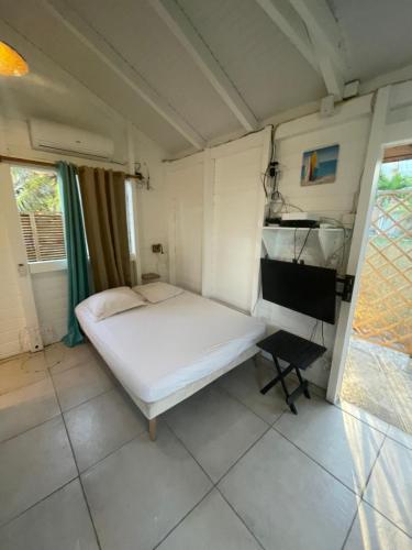 een kleine slaapkamer met een bed en een bureau bij 2 Bungalows au bord de la plage de montal a moule loués individuellement ou ensemble in Le Moule