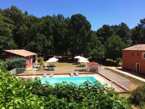 a swimming pool with chairs and umbrellas in a yard at Hotel Les Ambres in Roussillon