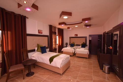 a hotel room with three beds and a television at Petra Guests Hotel in Wadi Musa