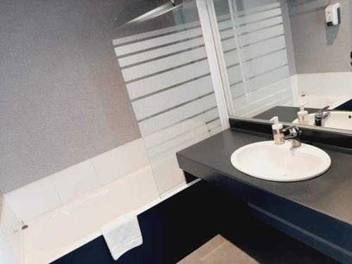 een badkamer met een wastafel en een bad bij Fasthotel L'Eldorado in Sébazac-Concourès