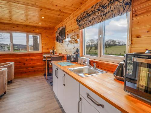 una cocina con fregadero y 2 ventanas en una cabaña en Stag Lodge Pod, en Welshpool