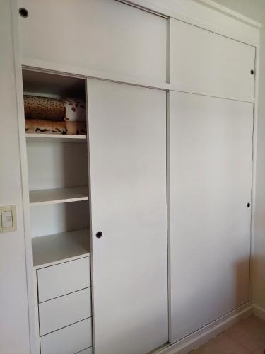 a white closet with glass doors and shelves at Dpto. luminoso, céntrico, nuevo: LA SERENA in Tandil