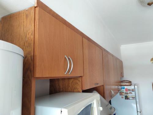 a kitchen with a wooden cabinet above a microwave at Dpto. luminoso, céntrico, nuevo: LA SERENA in Tandil