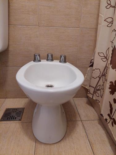 a white sink in a bathroom with a shower curtain at Dpto. luminoso, céntrico, nuevo: LA SERENA in Tandil
