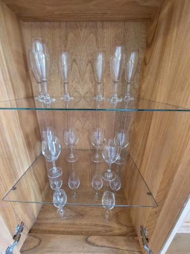 a glass shelf with wine glasses on a wooden table at Dpto. luminoso, céntrico, nuevo: LA SERENA in Tandil