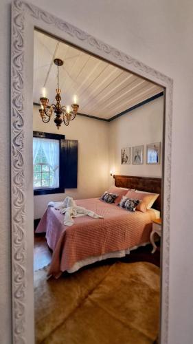 a bedroom with a large bed and a chandelier at HOTEL FAZENDA PACIENCIA in Santana dos Montes