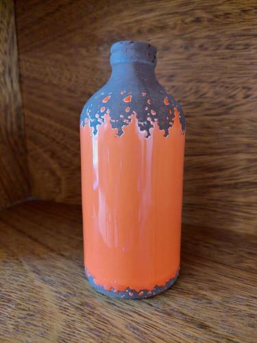 an orange vase sitting on top of a wooden floor at Dpto. luminoso, céntrico, nuevo: LA SERENA in Tandil